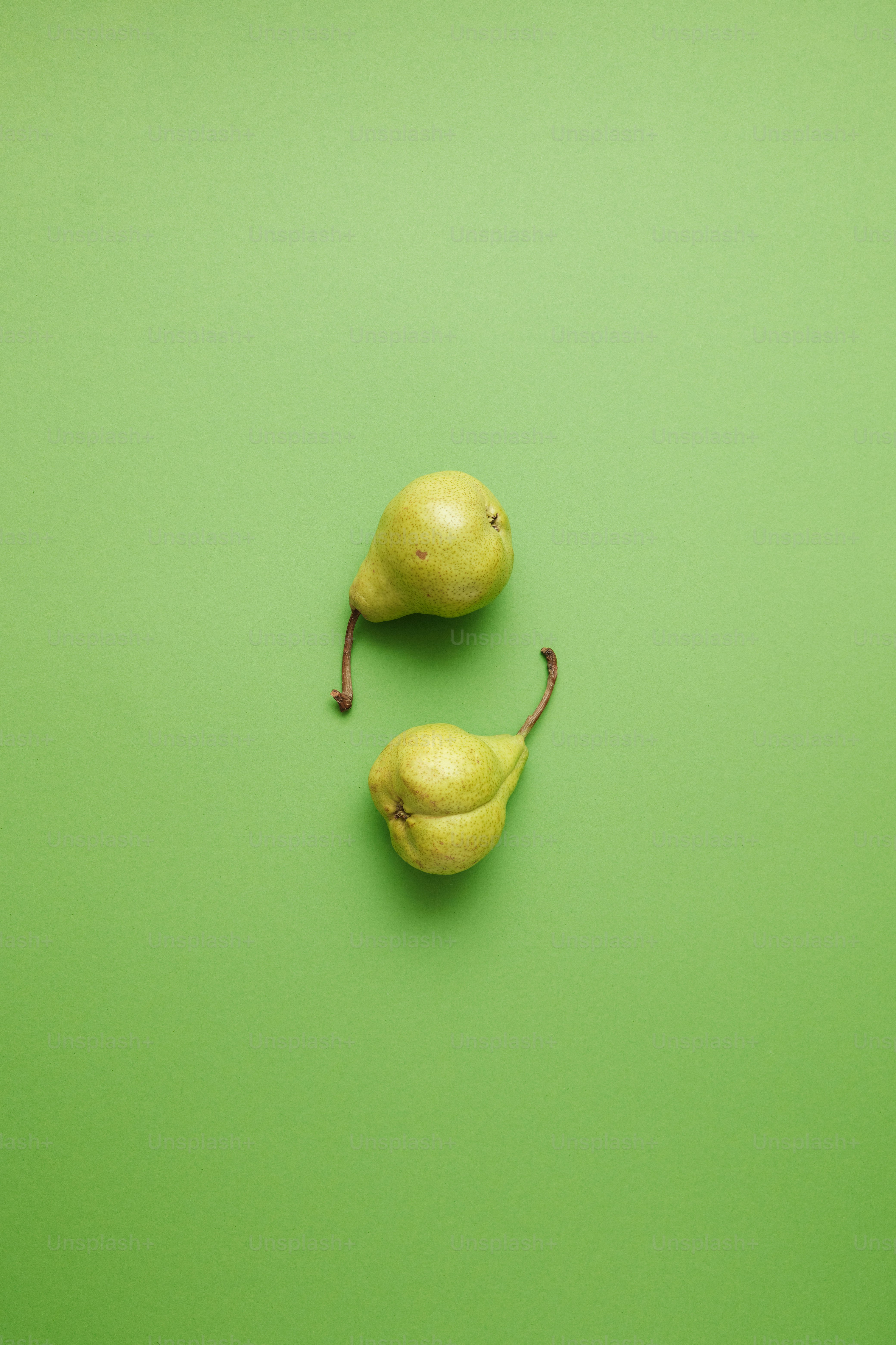 緑の表面の上に座っている梨のカップル