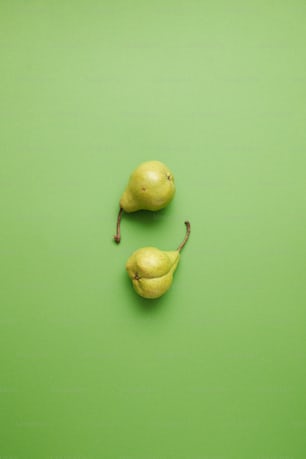 a couple of pears sitting on top of a green surface
