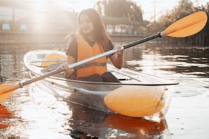 a woman in a yellow life jacket paddling a canoe