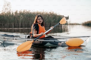 a woman in an orange life jacket paddling a kayak