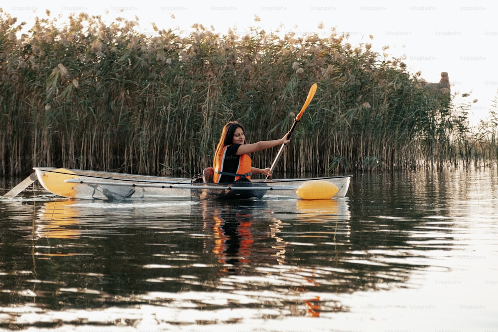 a woman in a yellow life jacket paddling a canoe