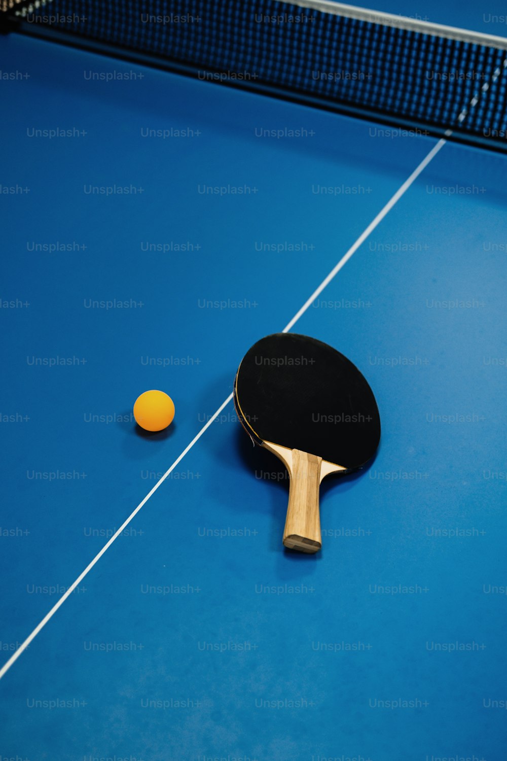 Une raquette de ping-pong et une balle de ping-pong sur une table bleue