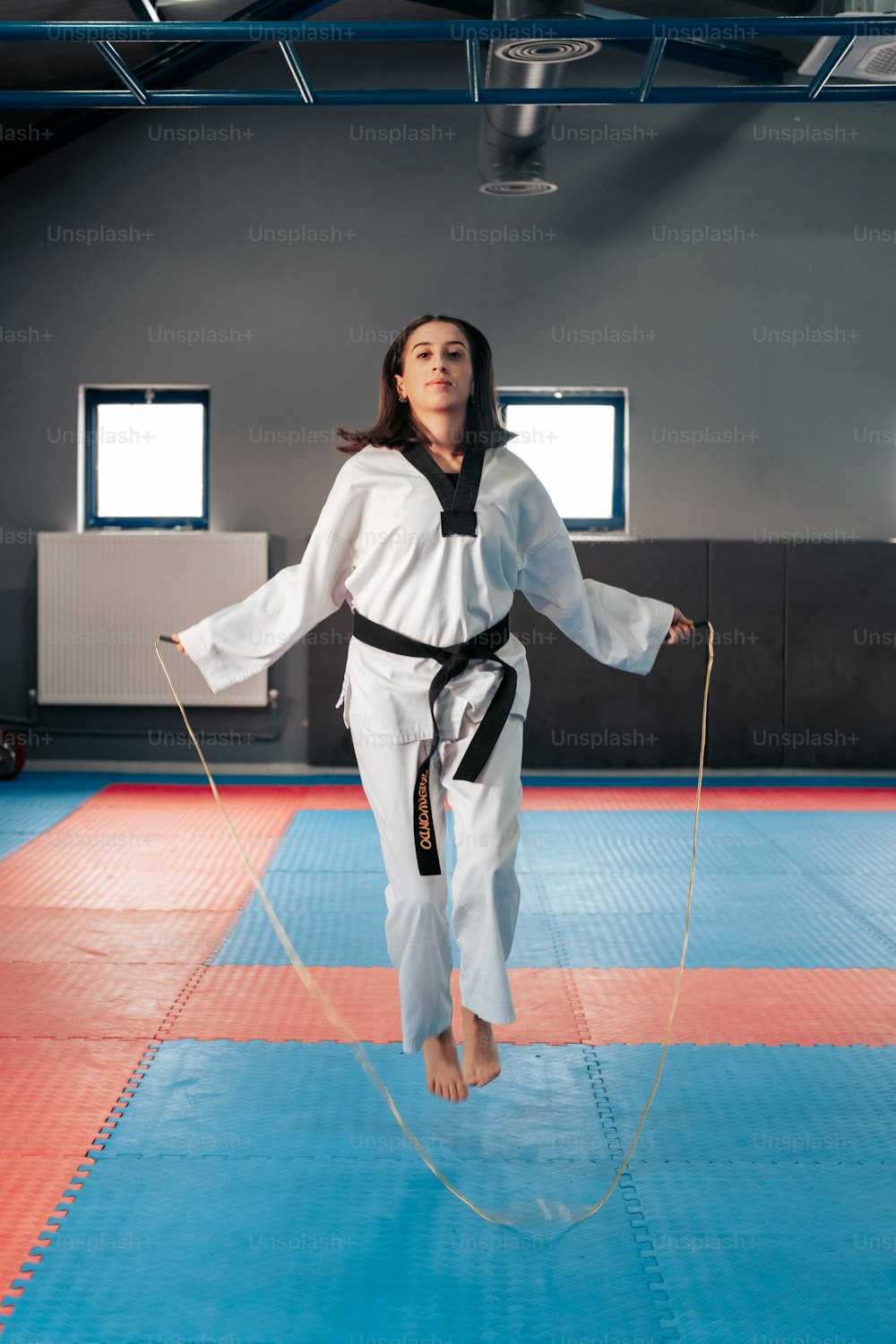 a woman standing on a blue mat with a black belt