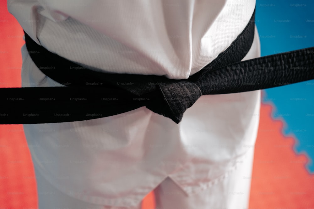 a person wearing white pants and a black belt