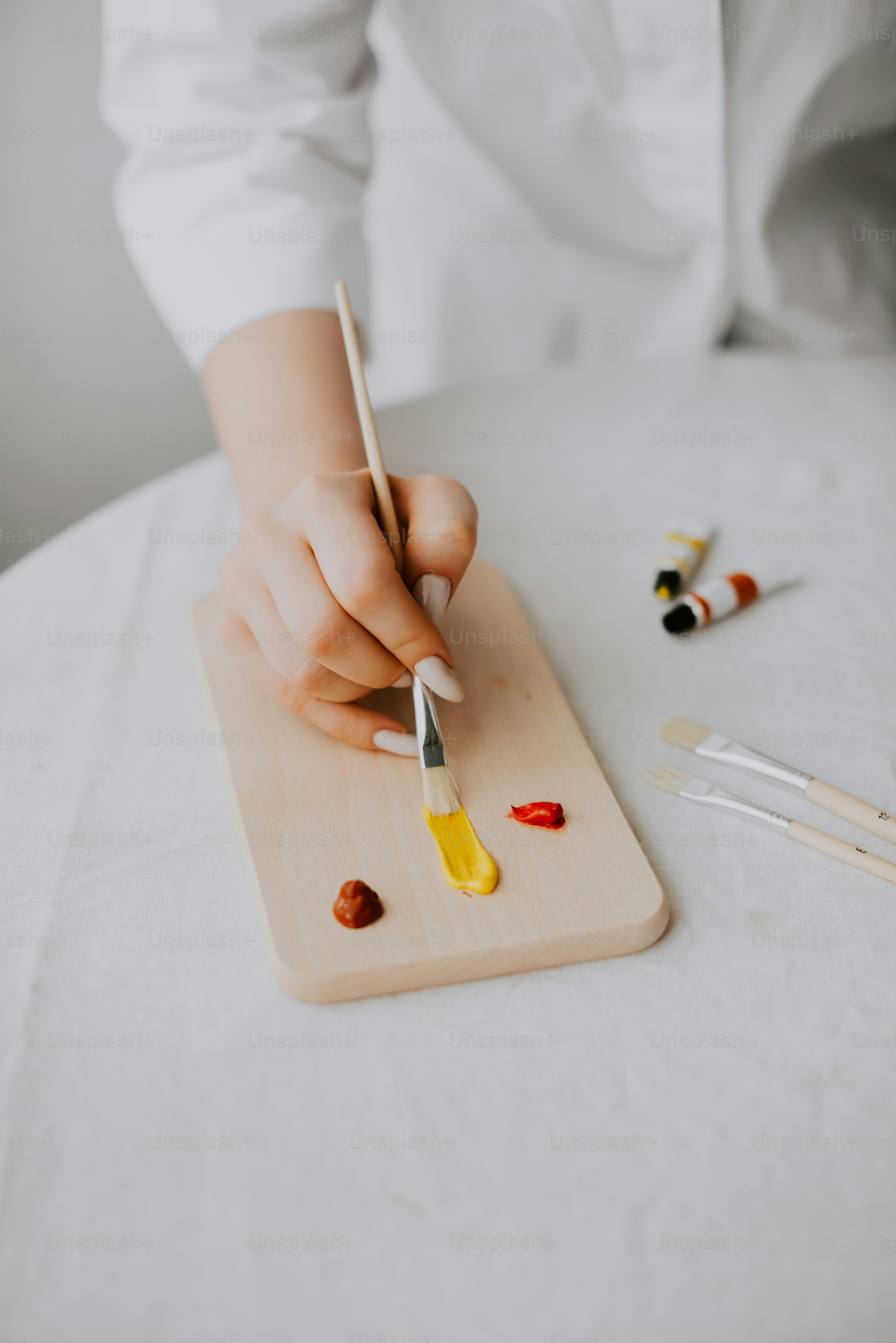 a person holding a knife and painting on a wooden board