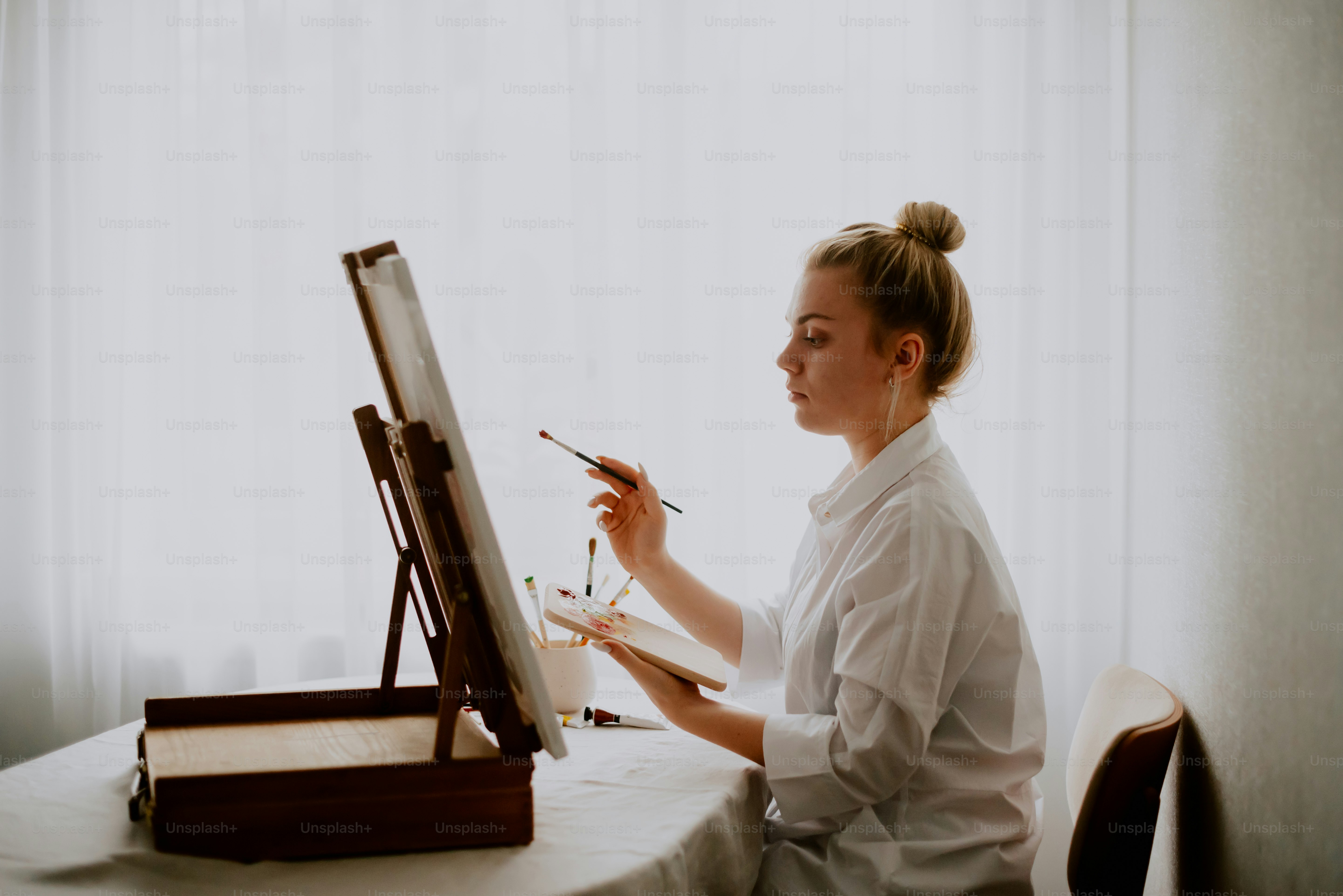 a woman sitting at a table with a brush and palette