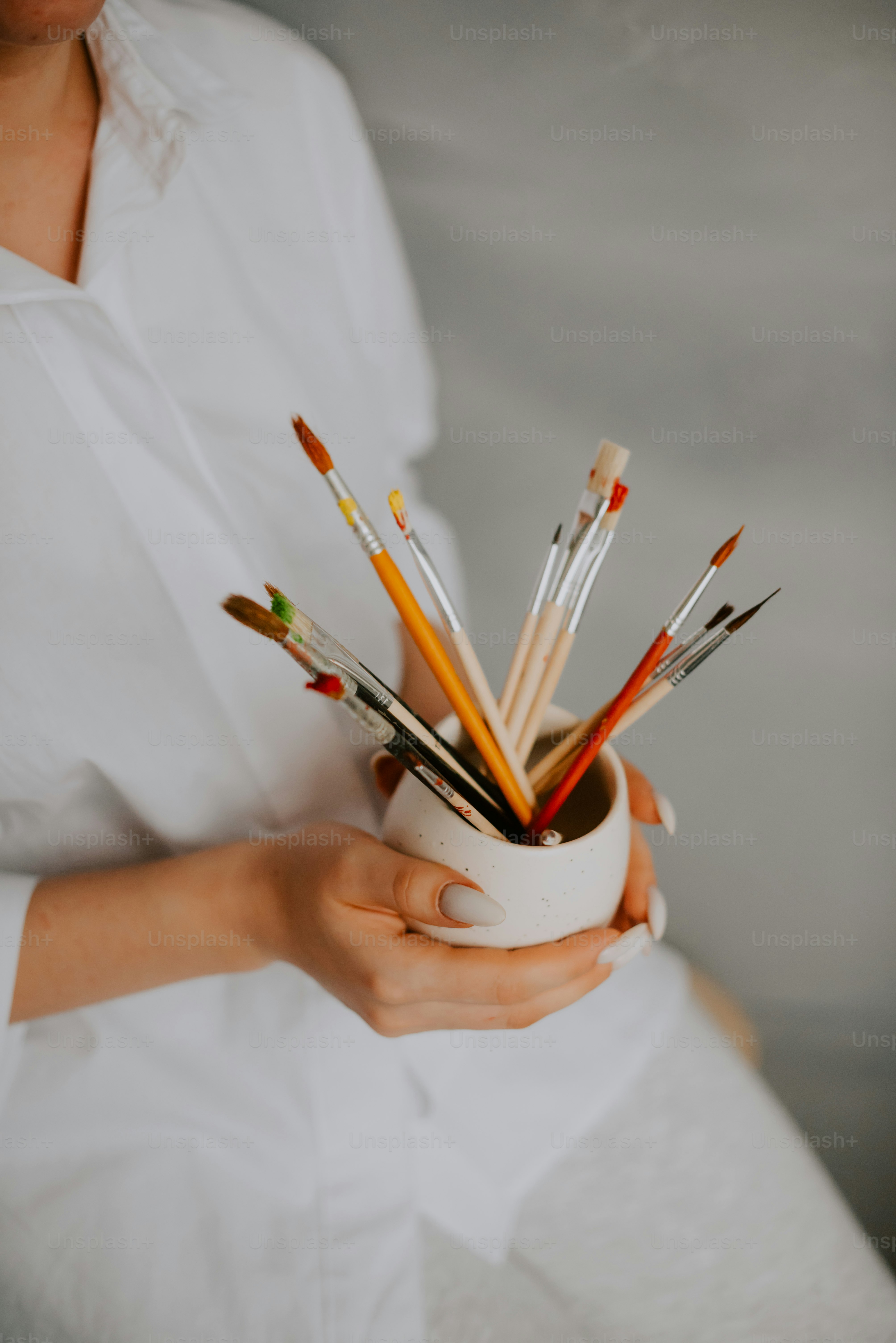a woman holding a cup filled with lots of pencils