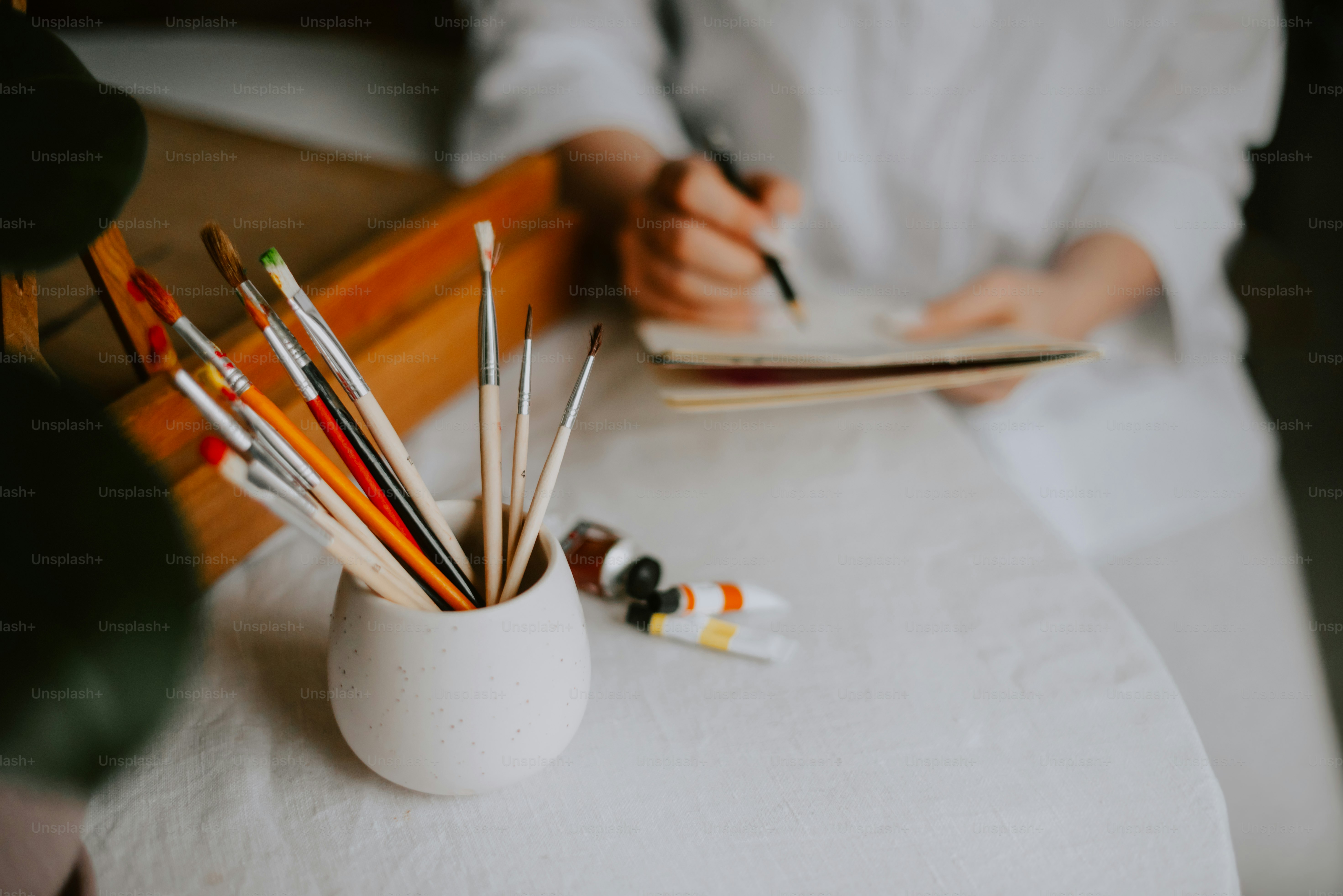 une personne assise à une table écrivant dans un cahier