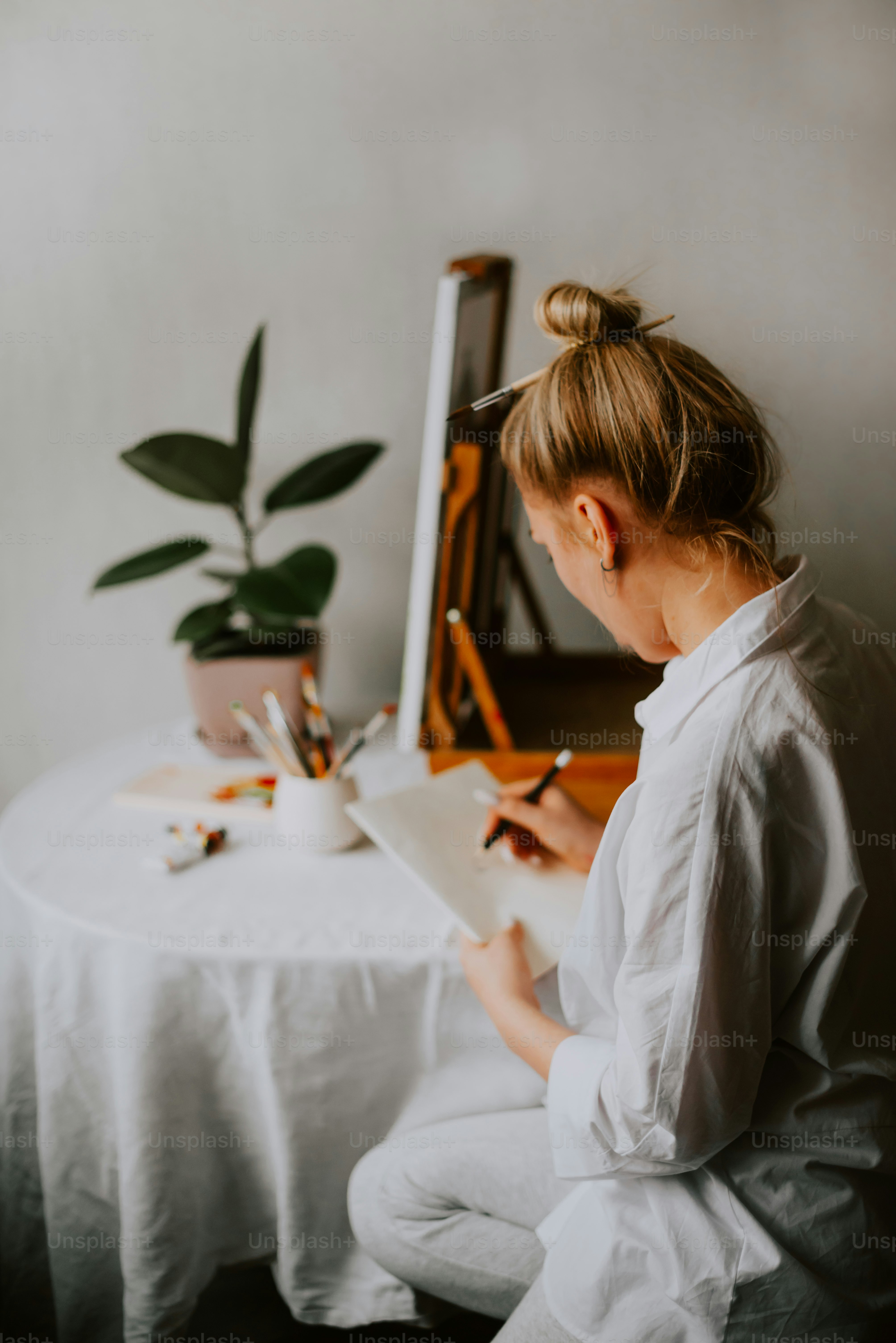 une femme assise à une table écrivant sur un morceau de papier