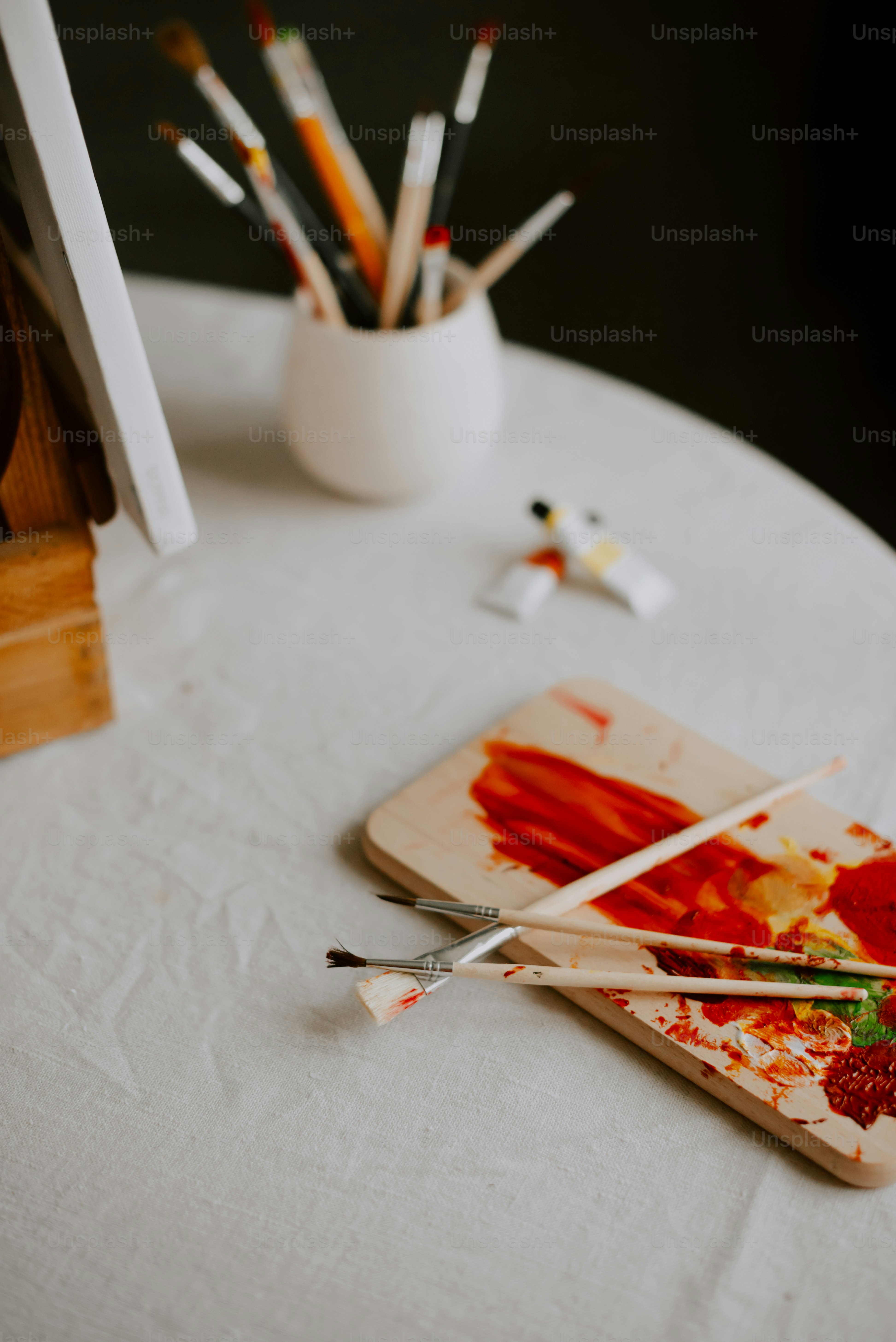 une table blanche surmontée de peinture et de pinceaux