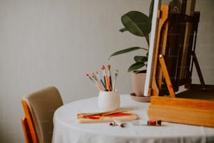 Una mesa blanca coronada con un jarrón blanco lleno de lápices