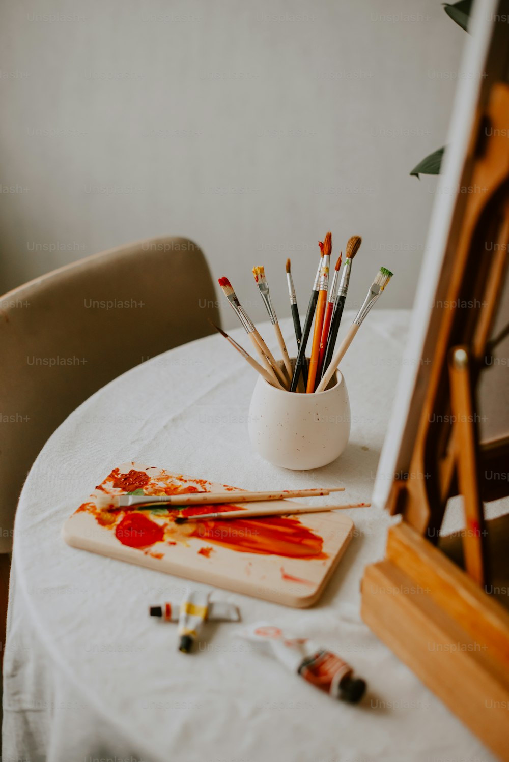 a white table topped with lots of paint and brushes