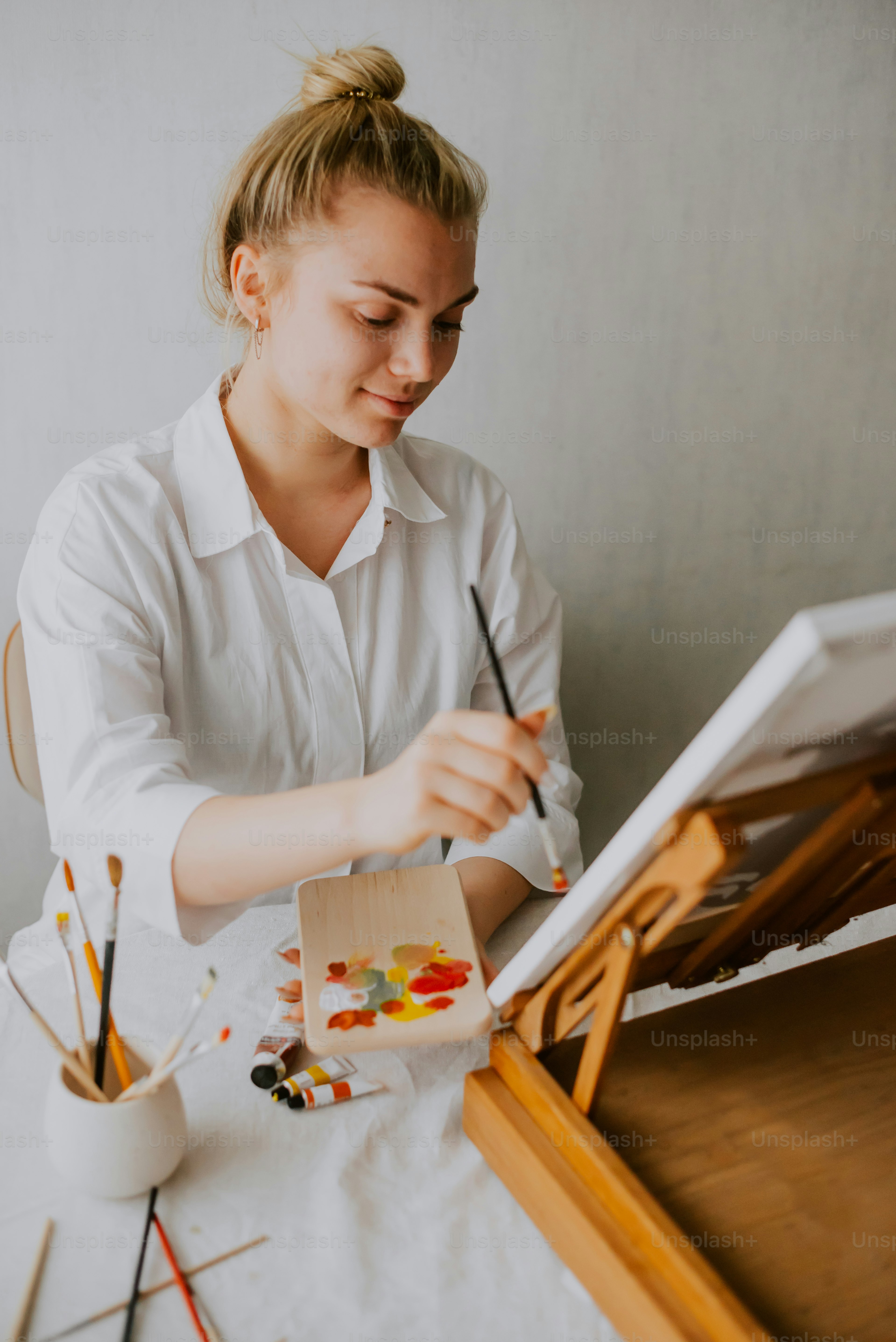 絵筆とパレットを持ってテーブルに座っている女性
