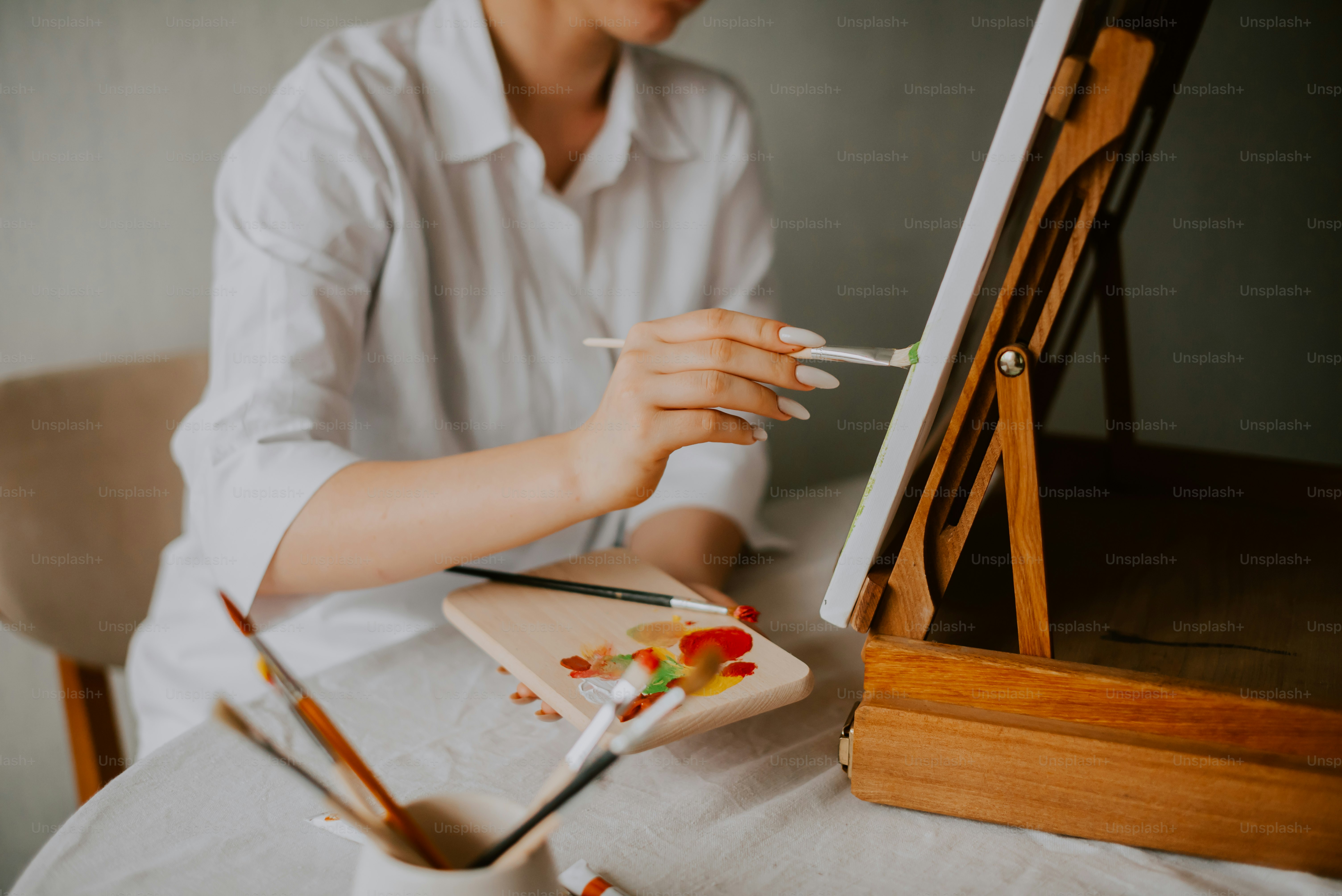 Une femme assise à une table tenant un pinceau