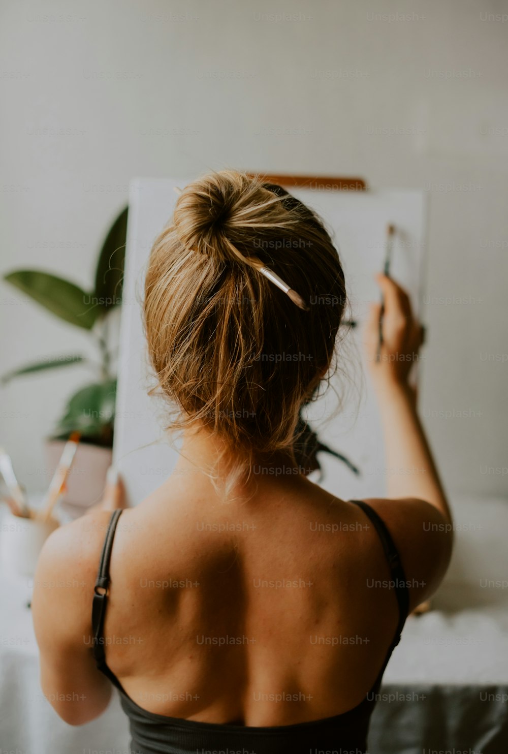 a woman in a black tank top writing on a piece of paper