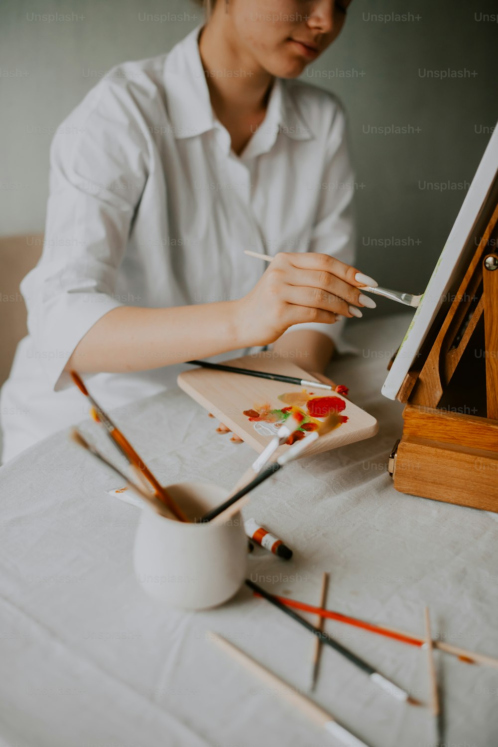 a woman sitting at a table with paint and brushes