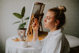 una donna seduta a un tavolo che dipinge un quadro