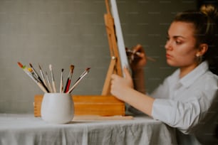 a woman is painting a picture on a easel