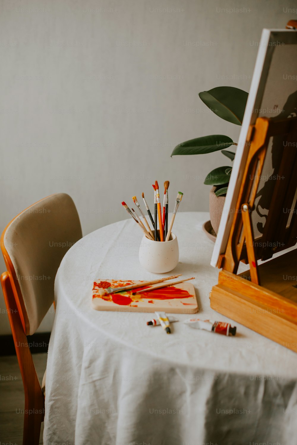 a white table with a white table cloth and a white vase filled with pencils