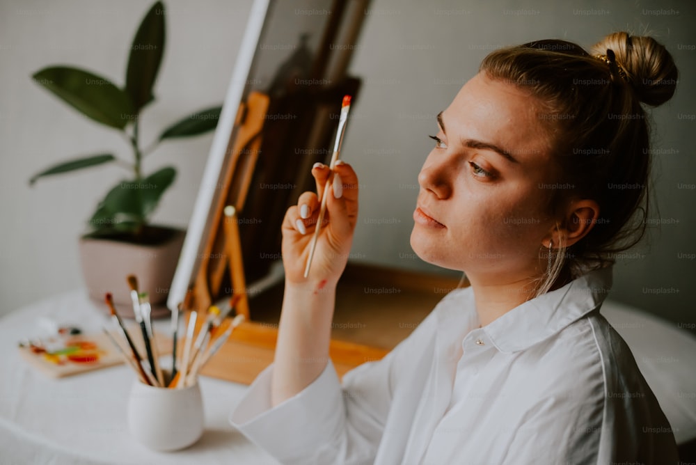 a woman holding a paintbrush in front of an easel