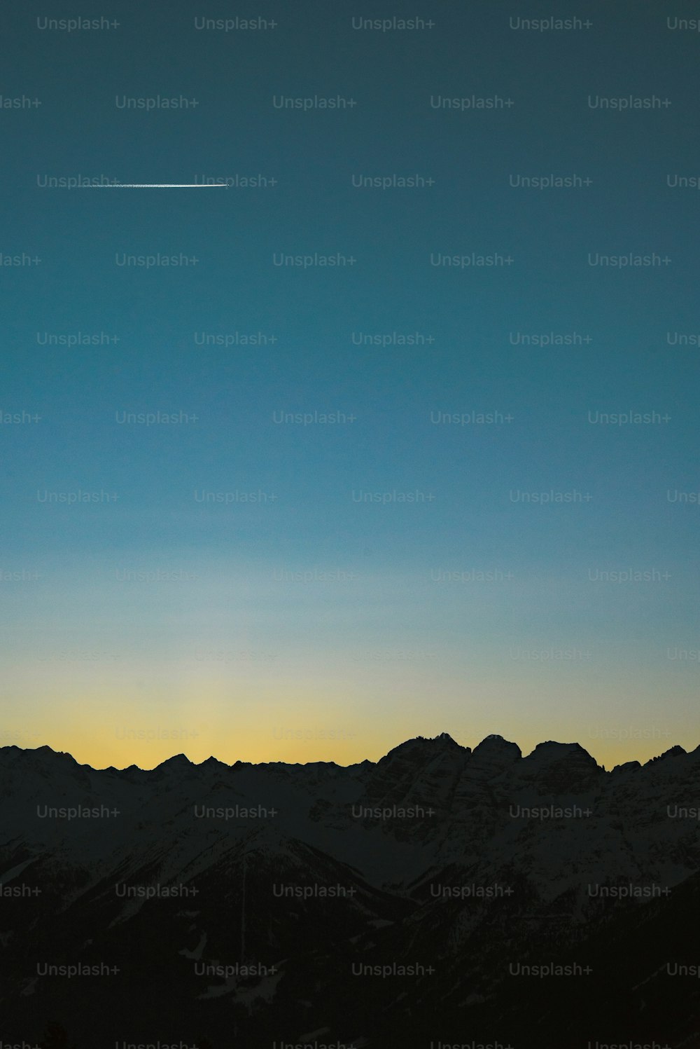 a plane flying in the sky over a mountain range