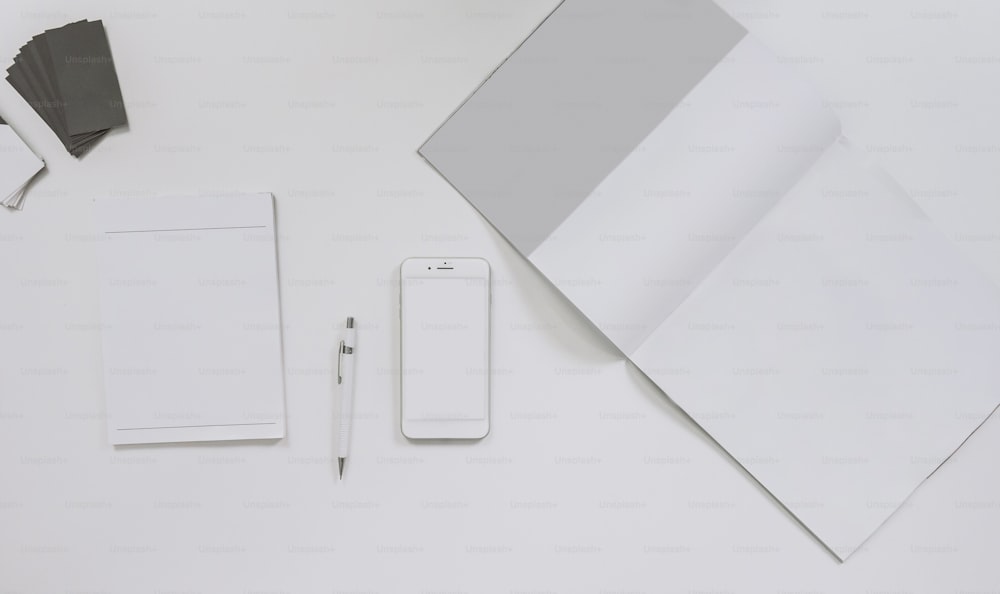 una mesa con un cuaderno, bolígrafo, teléfono y papel