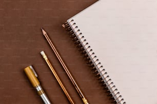Ein Notizbuch, Bleistifte und ein Apfel auf einem Tisch
