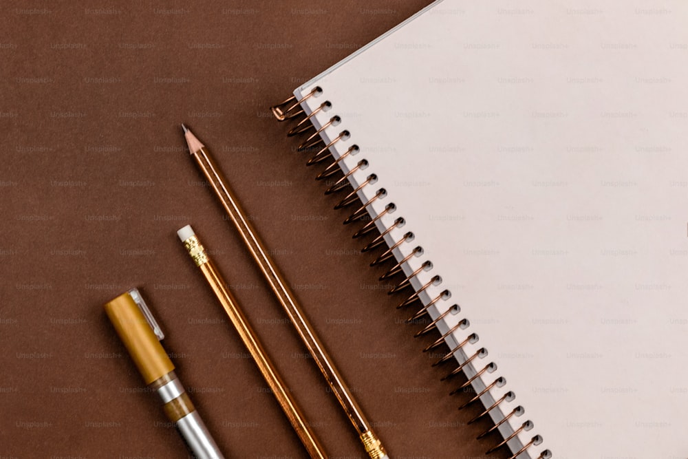 un cuaderno, lápices y una manzana sobre una mesa