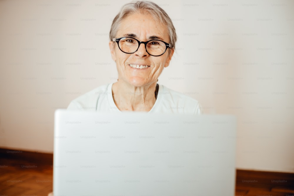 안경을 쓴 나이든 여성이 노트북을 보고 있다