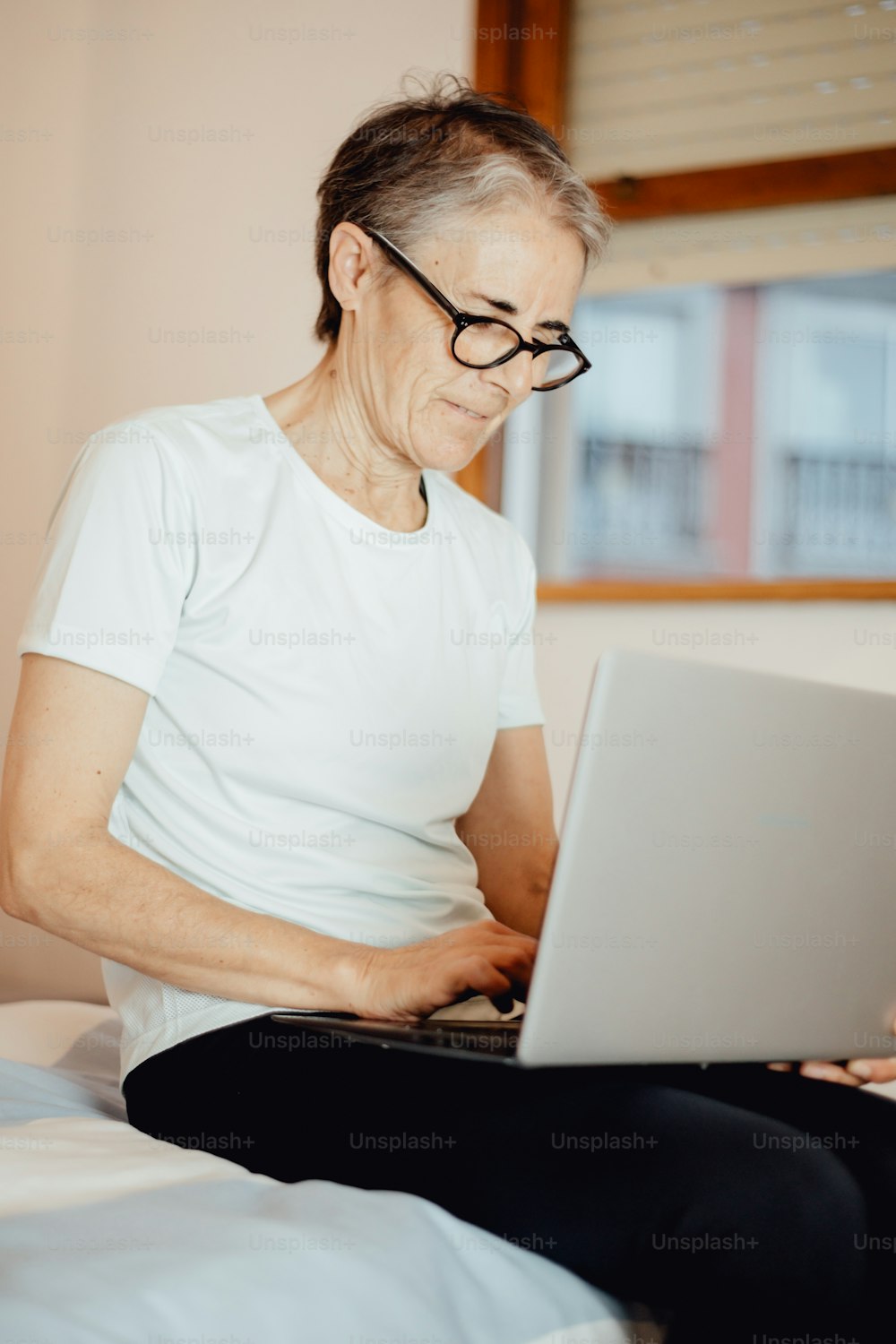 una donna seduta su un letto usando un computer portatile