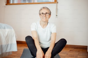 a woman sitting on a yoga mat in a room