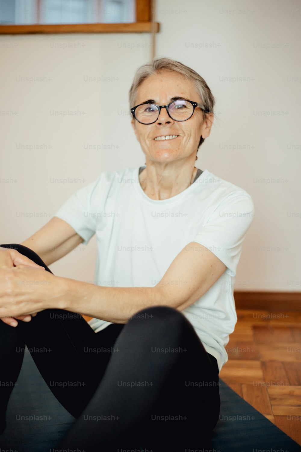an older woman sitting on a yoga mat