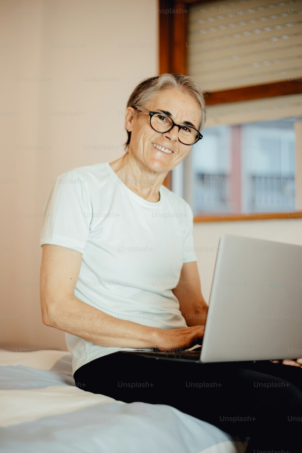 una donna seduta su un letto usando un computer portatile