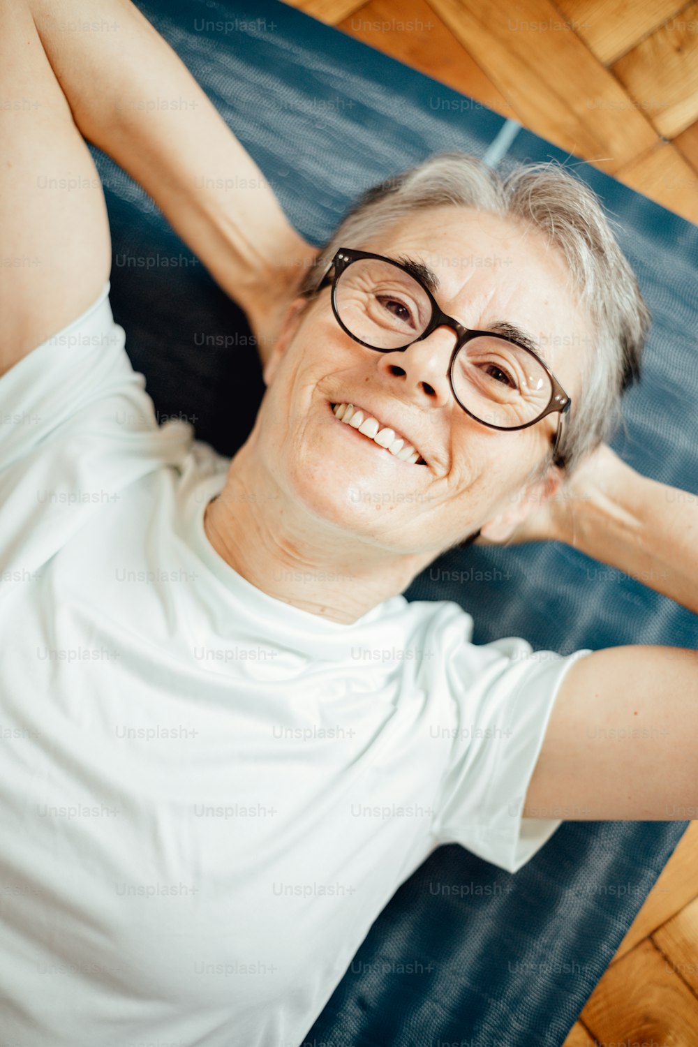 an older woman wearing glasses laying on a yoga mat