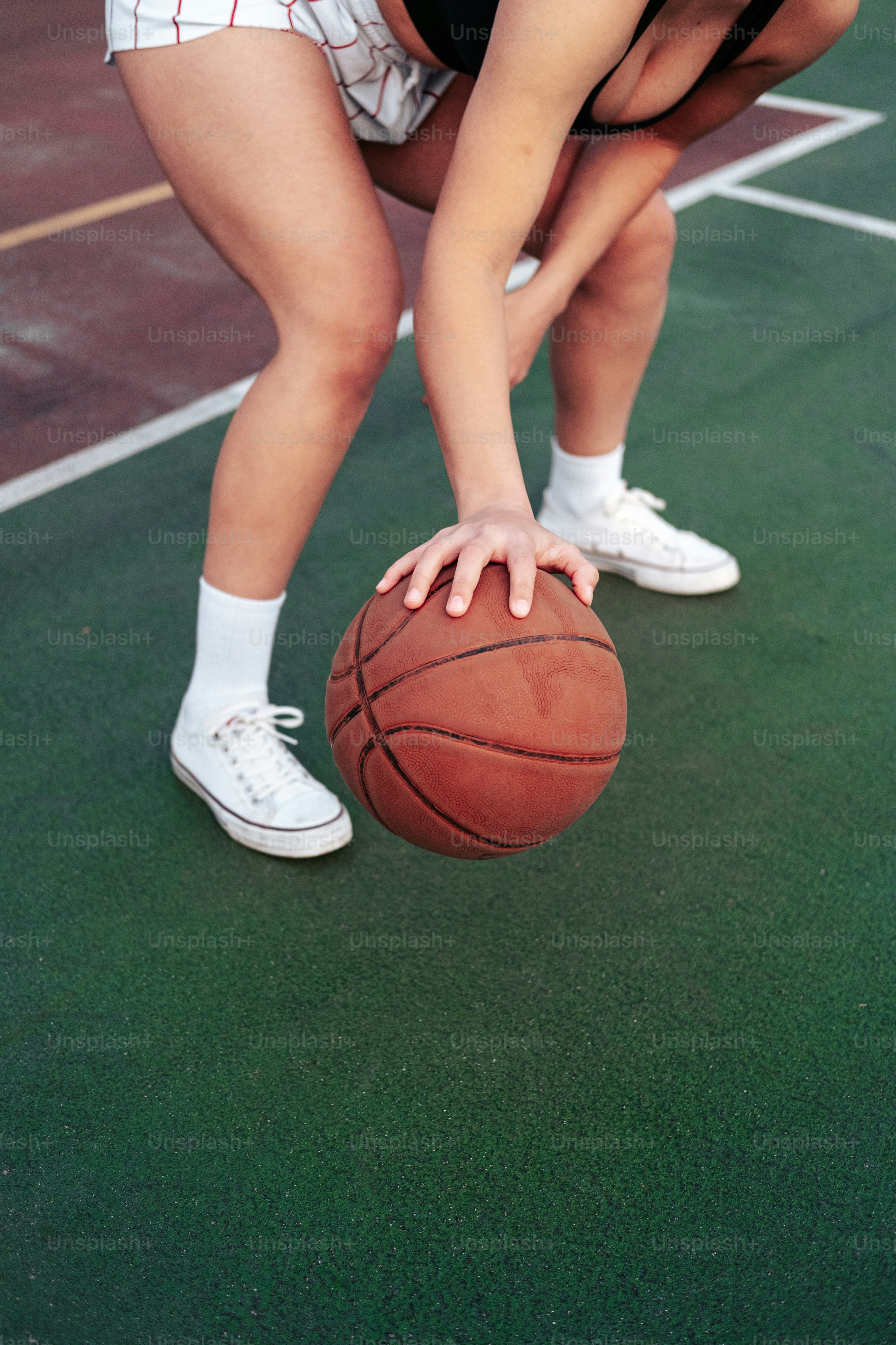 a woman bending over to pick up a basketball