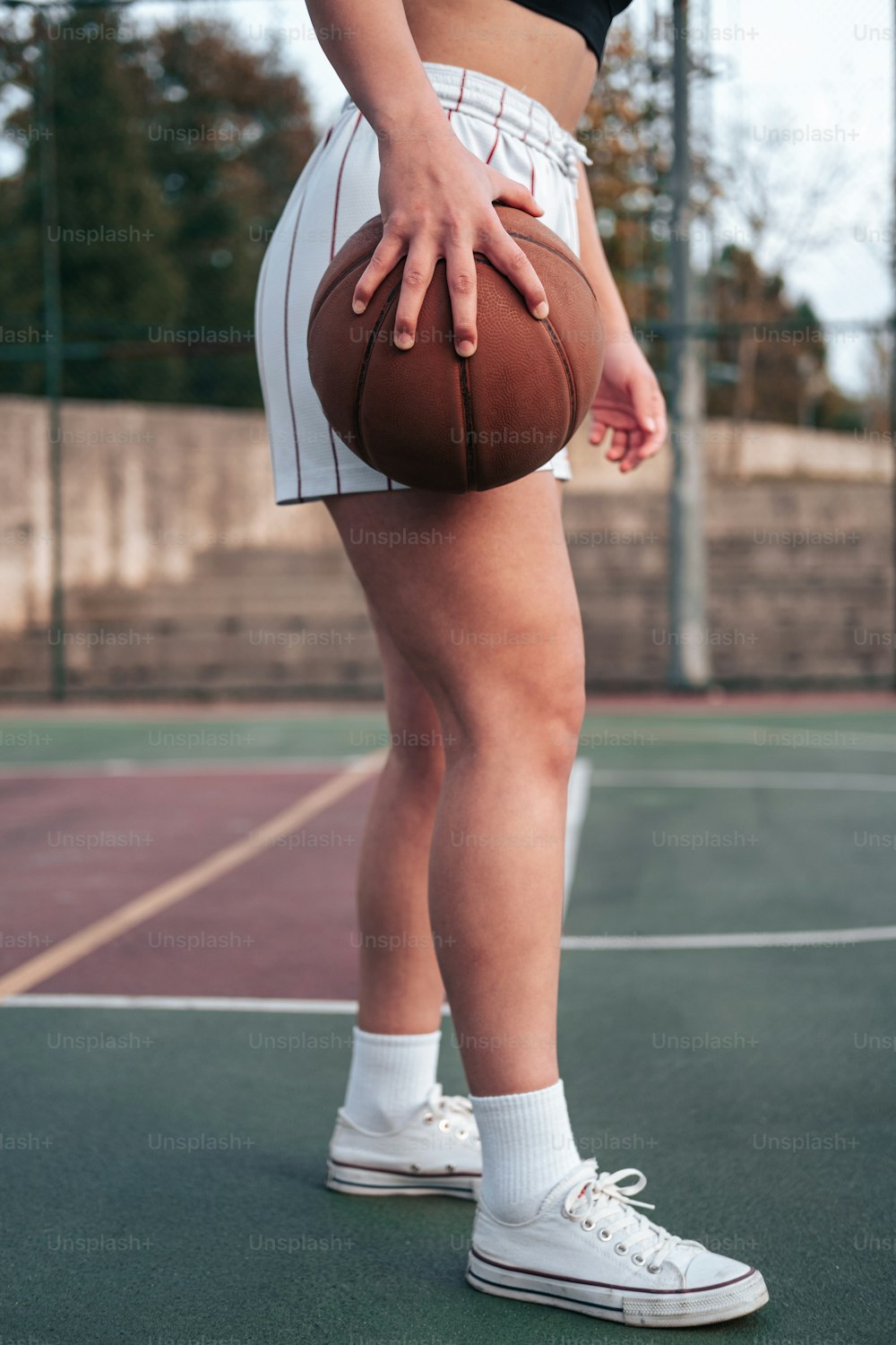 uma mulher segurando uma bola de basquete em cima de uma quadra de tênis