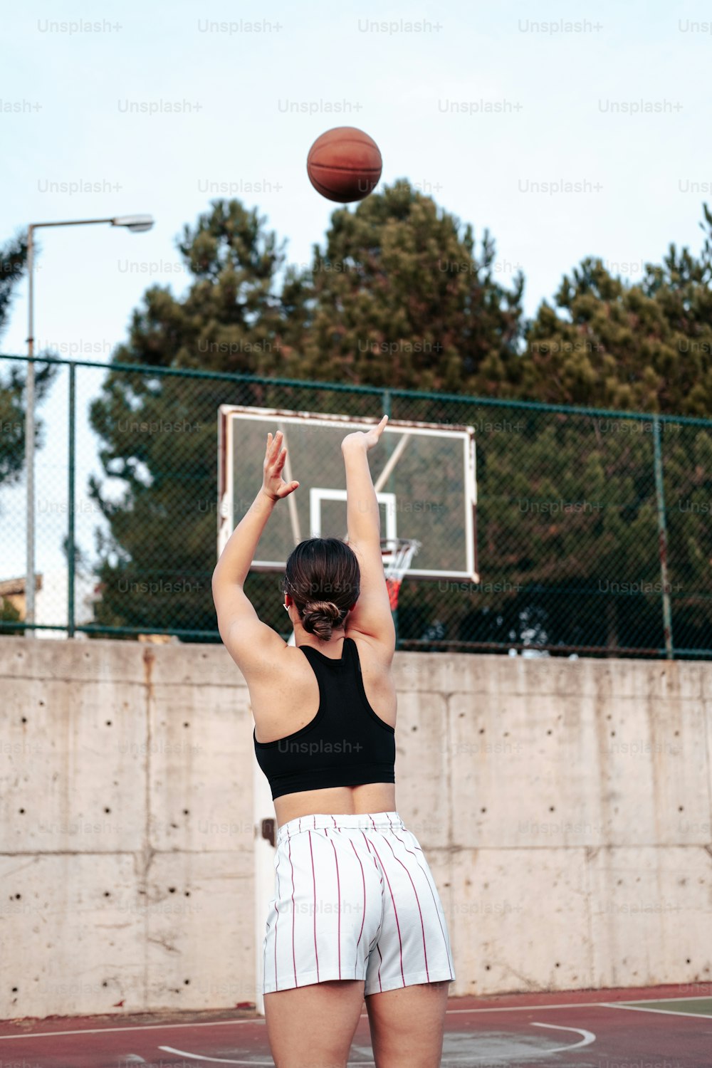 Une femme debout sur un terrain de basket-ball tenant un ballon de basket-ball