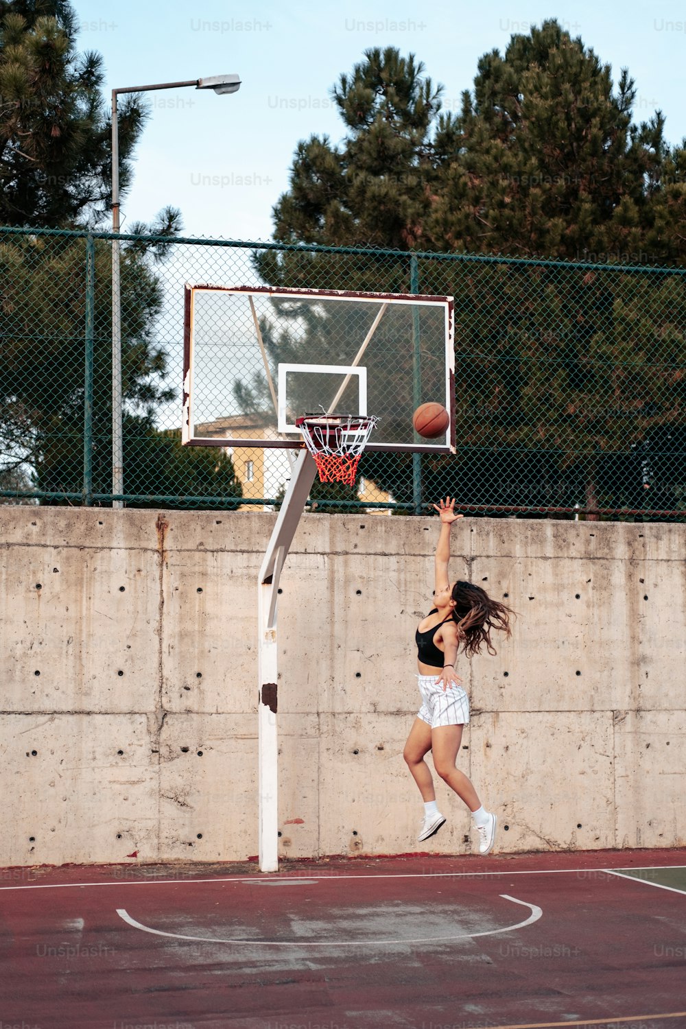Una mujer saltando para clavar una pelota de baloncesto