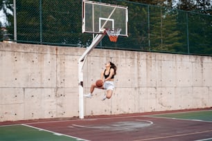 une personne qui saute en l’air pour dunker un ballon de basket