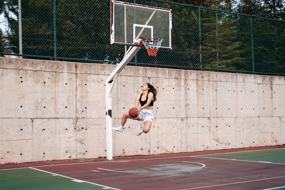 uma pessoa pulando no ar para enterrar uma bola de basquete