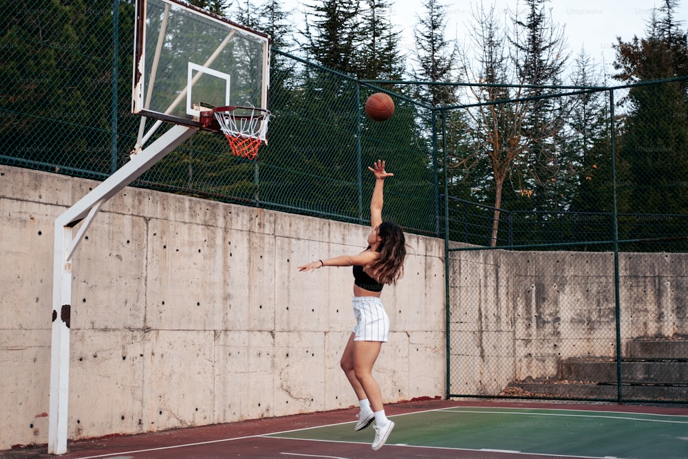 Une femme saute pour dunk un ballon de basket