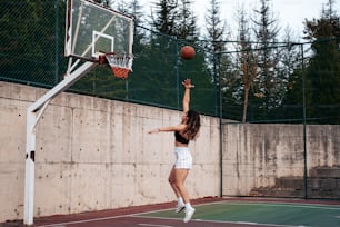 Une femme saute pour dunk un ballon de basket