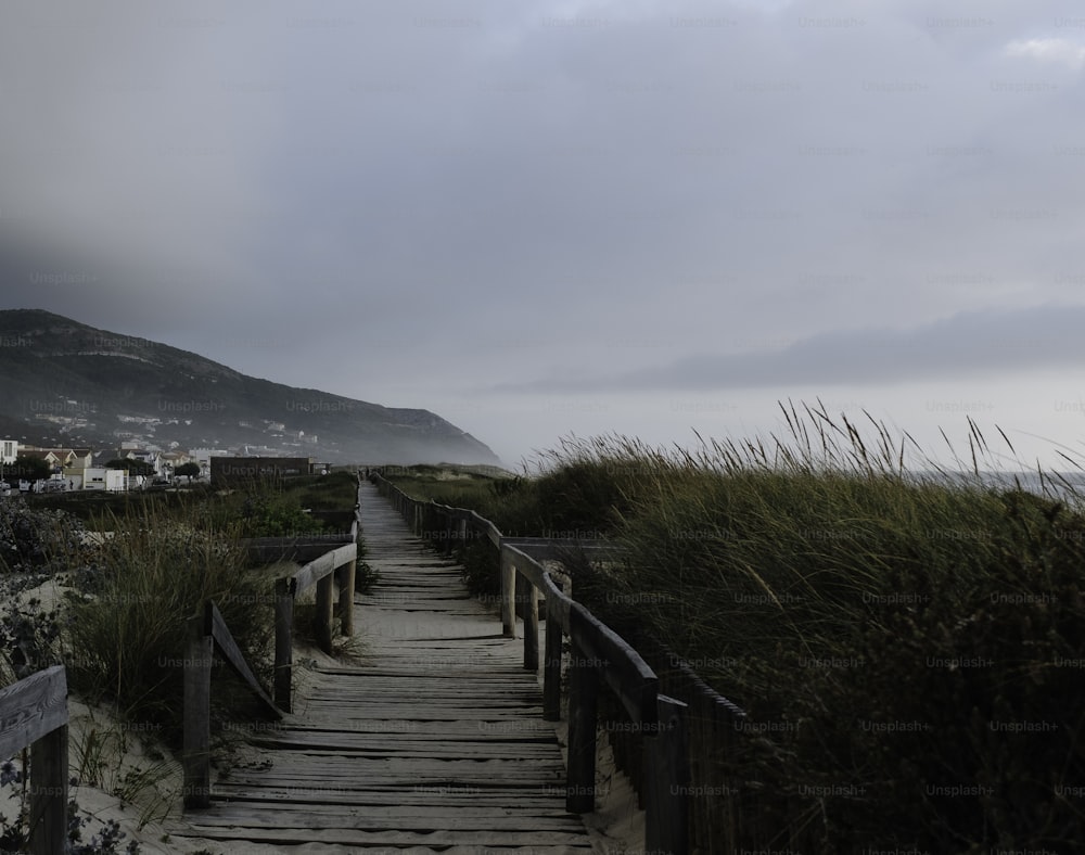 Una pasarela de madera que conduce a la playa con una montaña al fondo