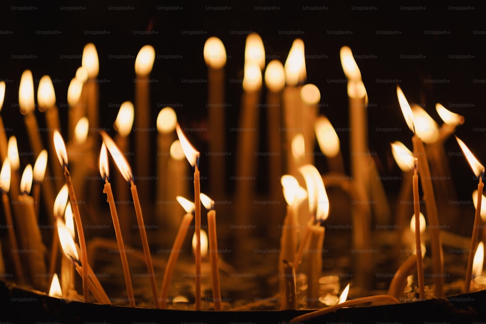 um monte de velas que são acesas no escuro