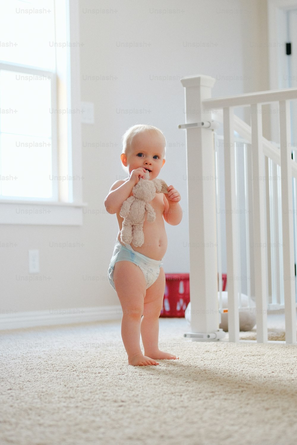 a baby in a diaper holding a teddy bear