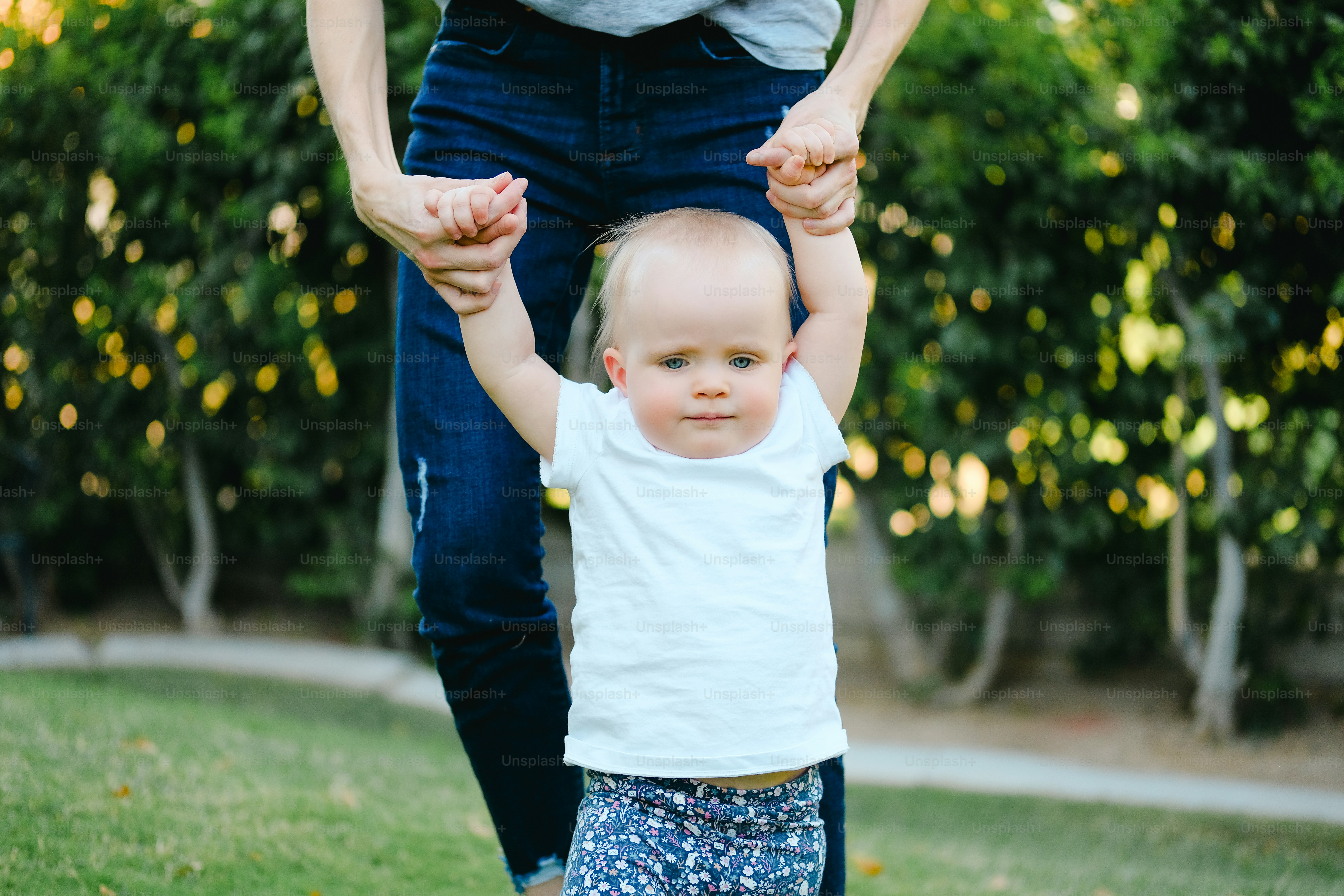 a woman holding the hands of a small child