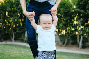 a woman holding the hands of a small child