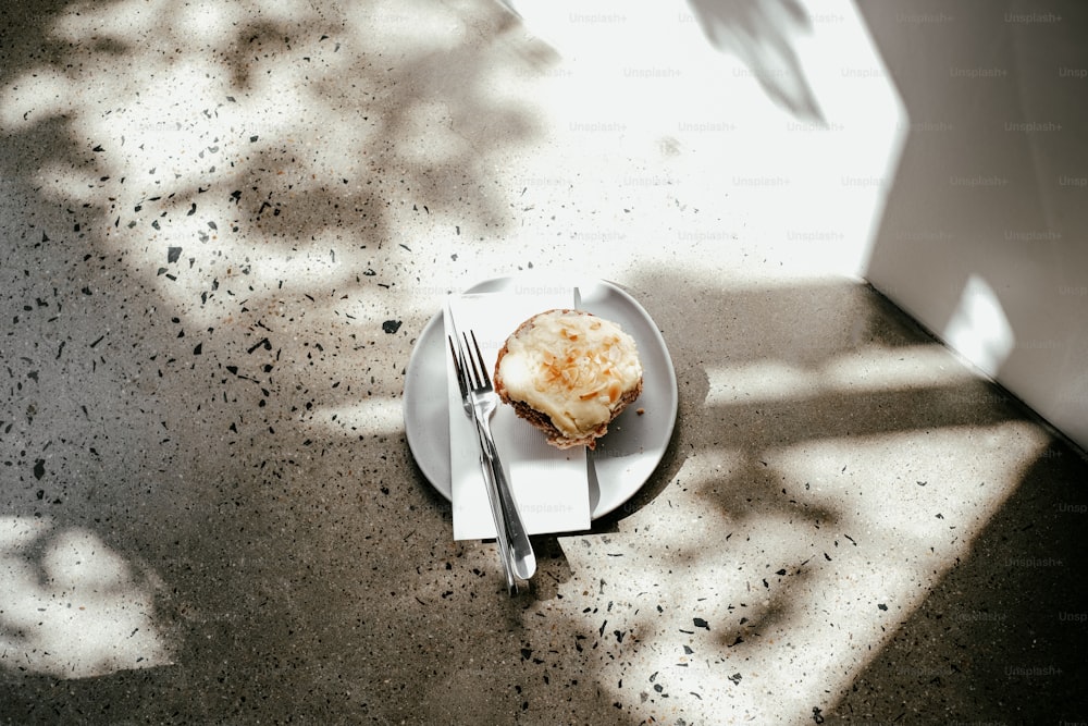 a white plate topped with a pastry next to a fork