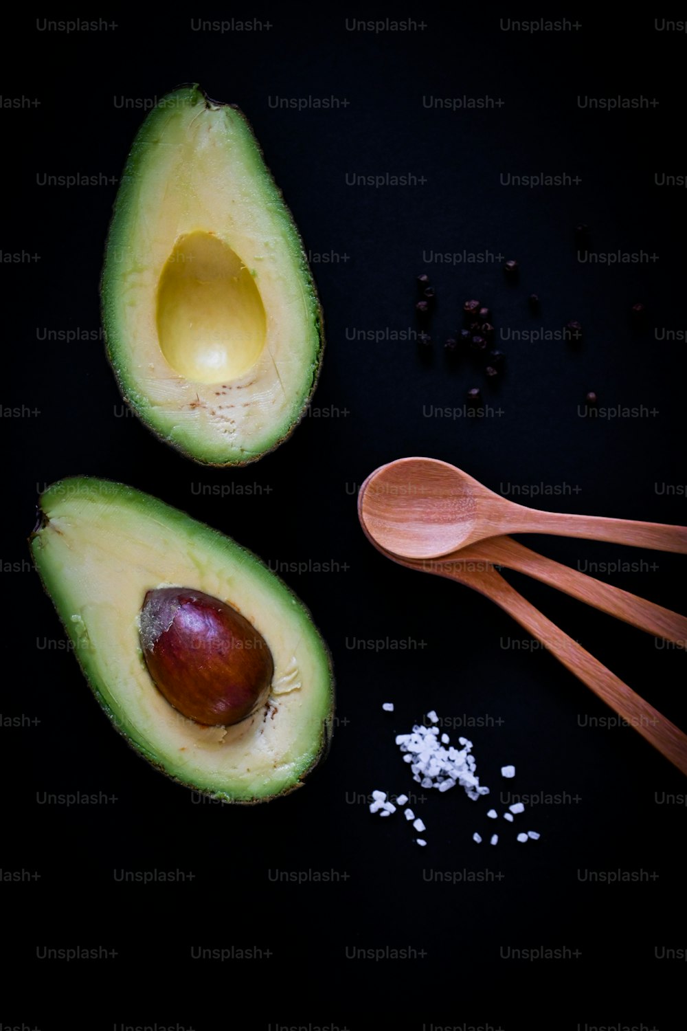 an avocado cut in half next to a spoon