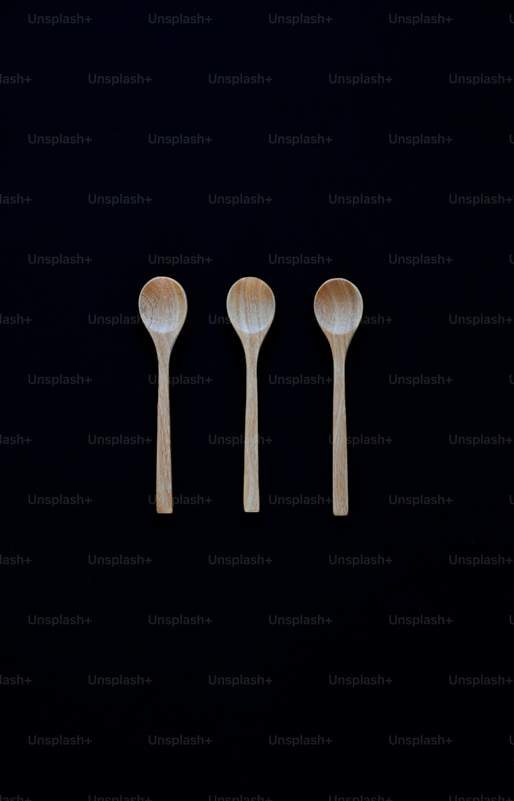 three wooden spoons on a black background